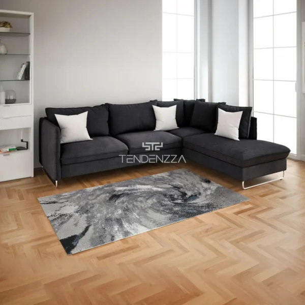 Alfombra Ottomano 6796A grey, una alfombra para la sala principal moderna. Piso en madera, sofá en ele color negro con una alfombra en forma rectangular de 2.30 mts de largo por 1.60 mts de ancho, con diseño en espiral en gris claro, gris oscuro, negro, azul y blanco. Alfombra importada de Turquía. Alfombras y tapetes en Bucaramanga